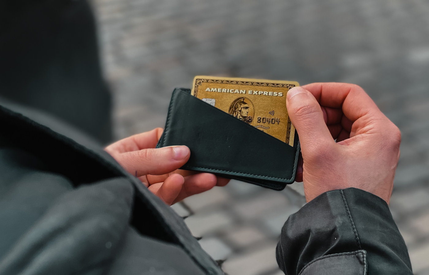 Mann hält Portemonnaie mit einer American Express Gold Card in den Händen