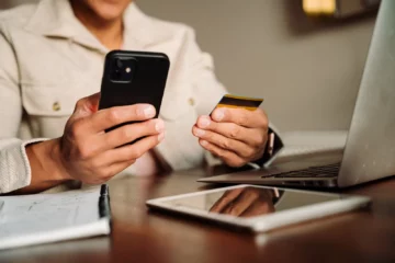 Mann hält eine Kreditkarte und sein iPhone in den Händen
